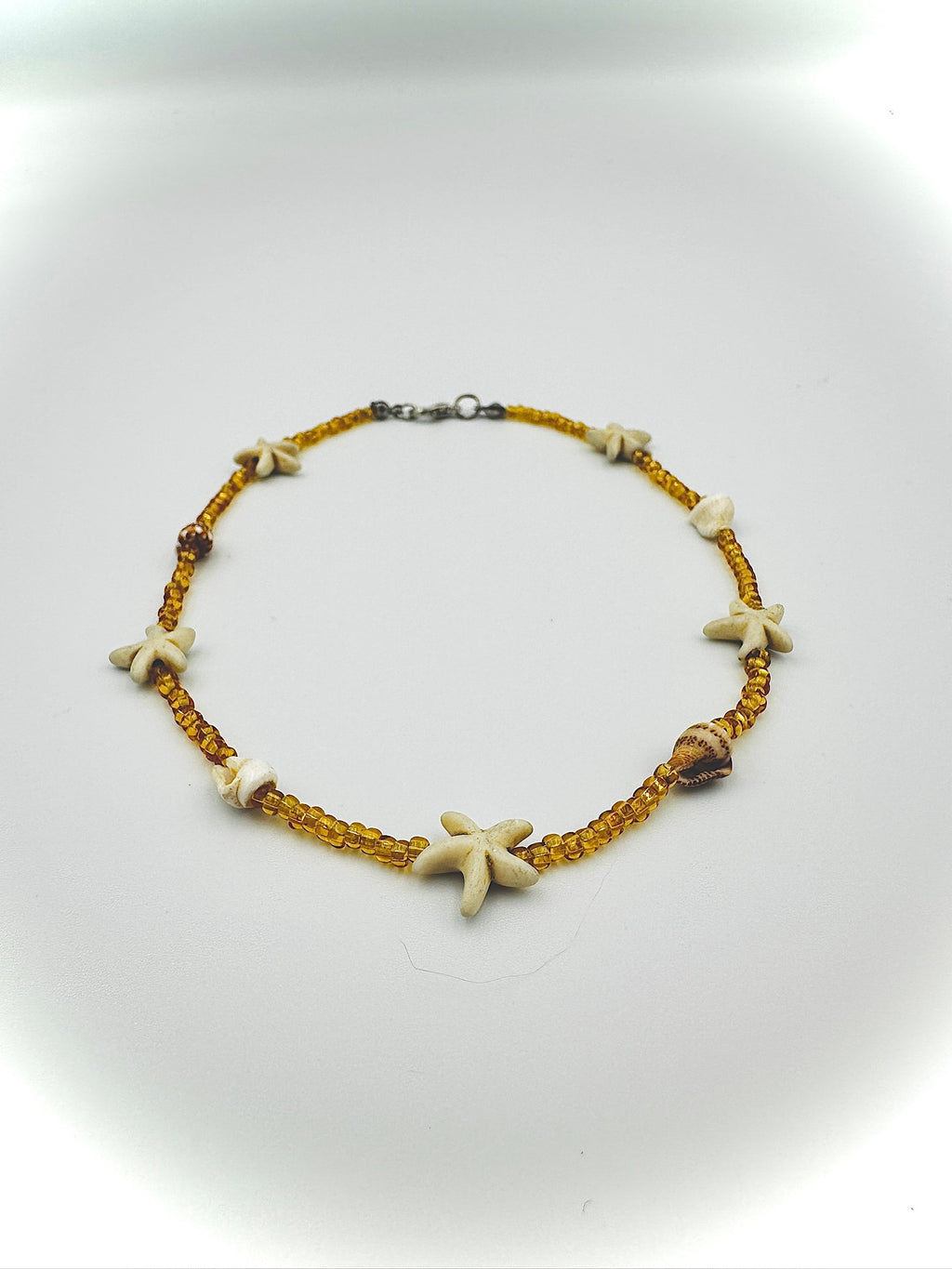 Starfish-themed anklet on a reflective surface
