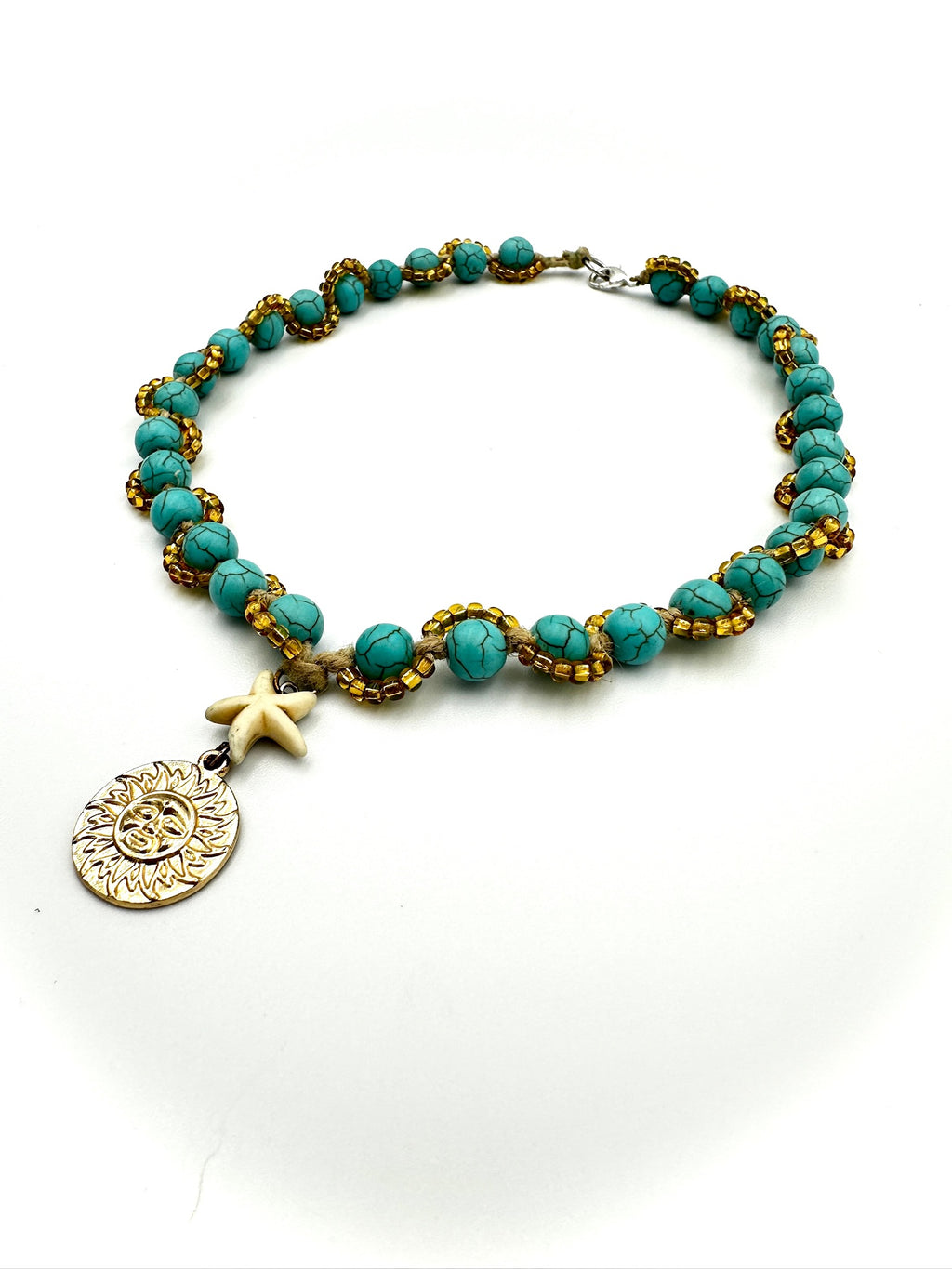 Turquoise beaded bracelet with gold accents and charms on a white background
