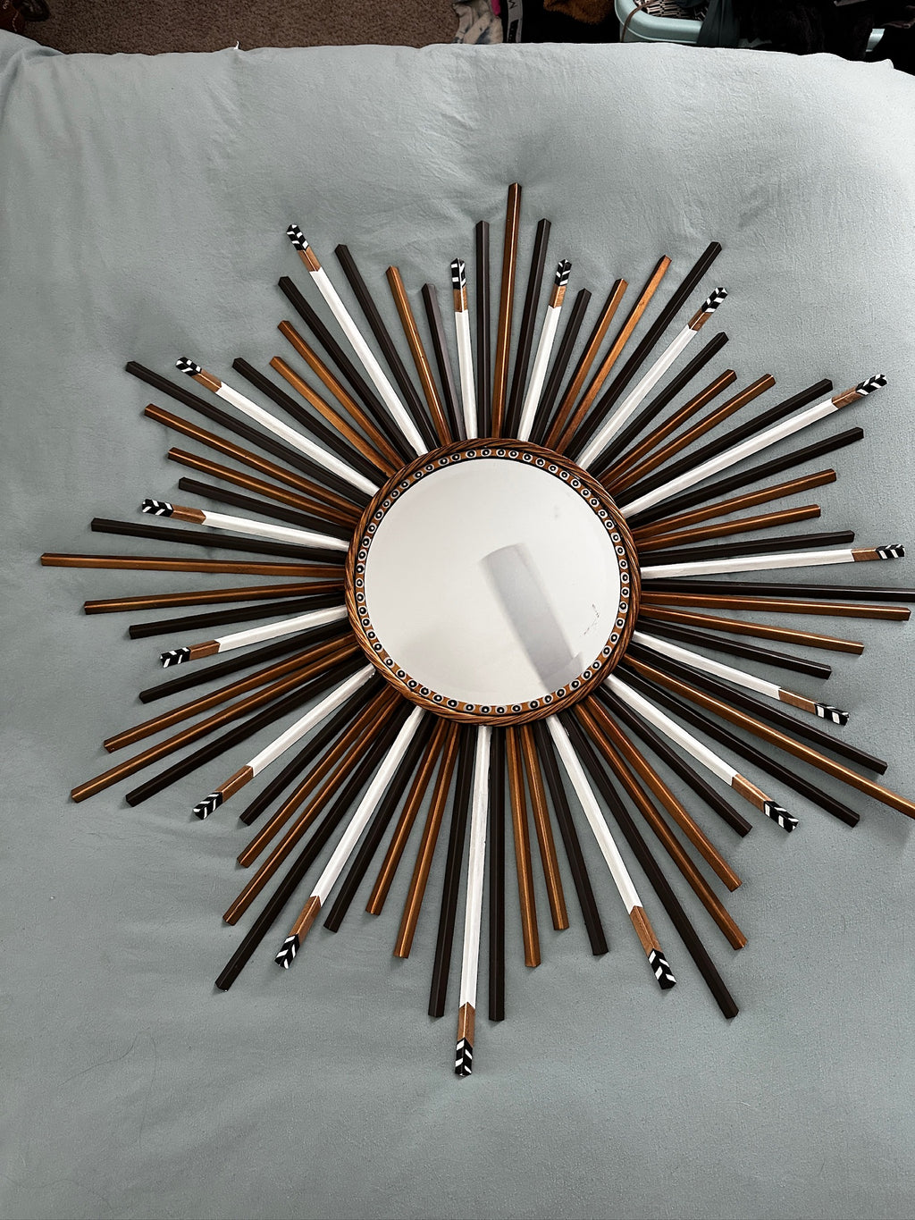 Decorative wall mirror with sunburst design on a light gray background
