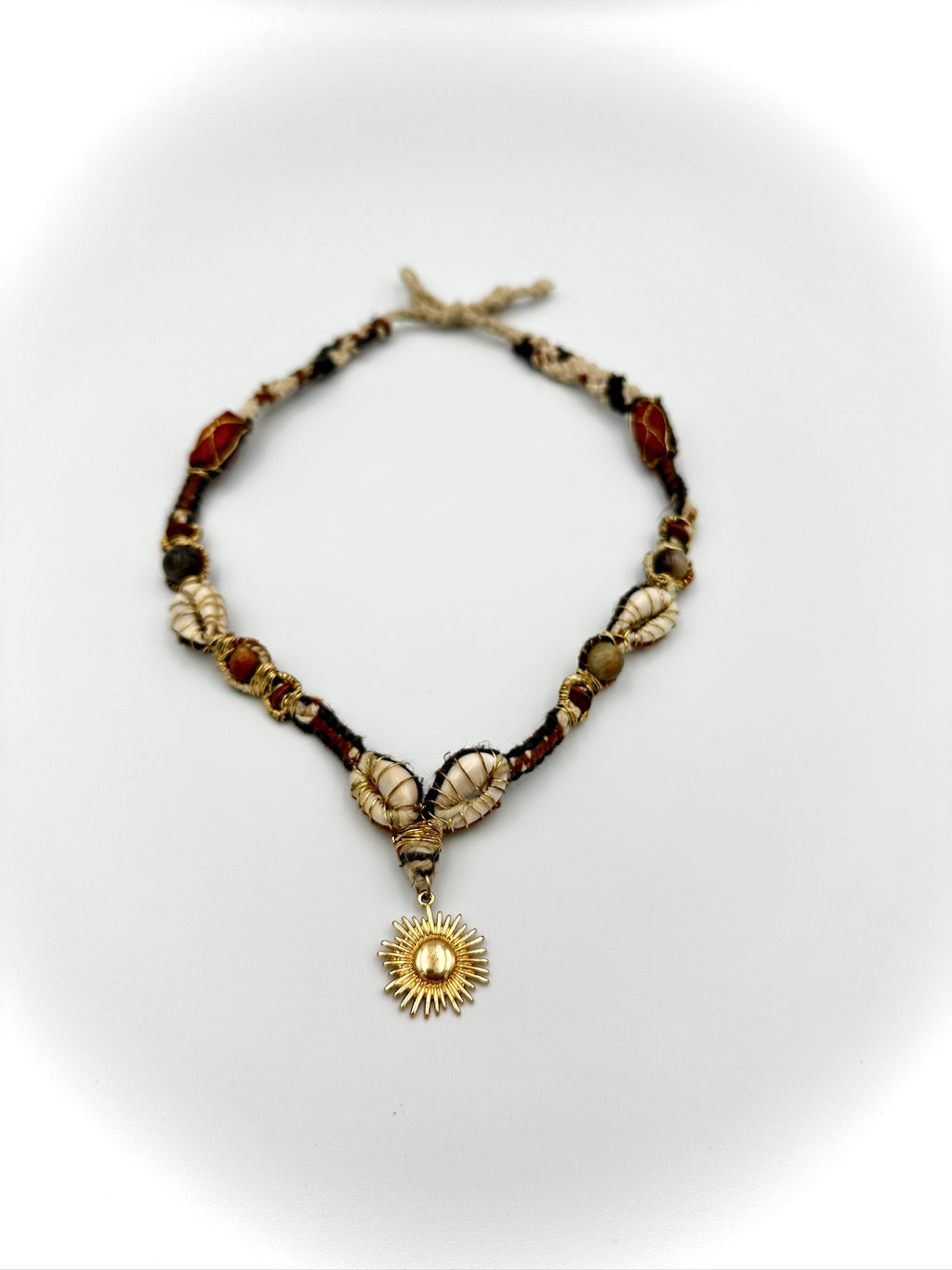 Necklace with shell and sun pendant on a white background