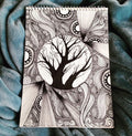 Notebook with a black and white tree design on a textured blue fabric background
