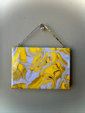 Abstract painting with yellow and white patterns on a gray wall