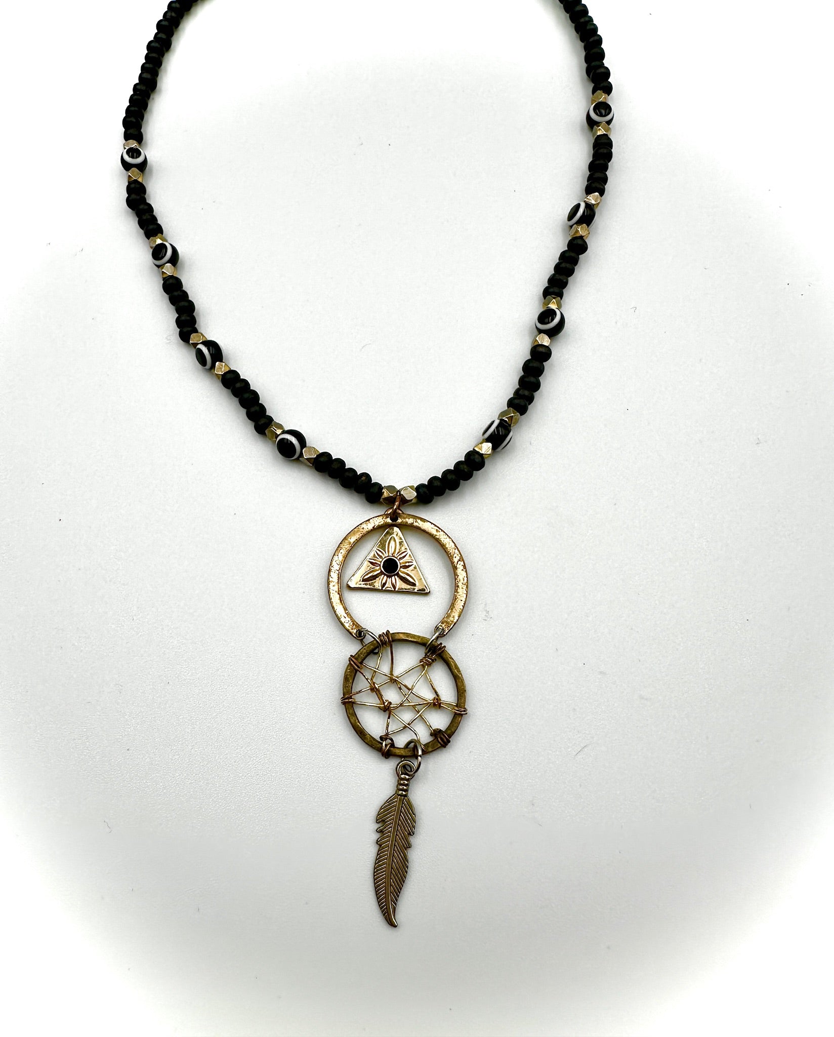 Necklace with black beaded chain and dreamcatcher pendant on a white background