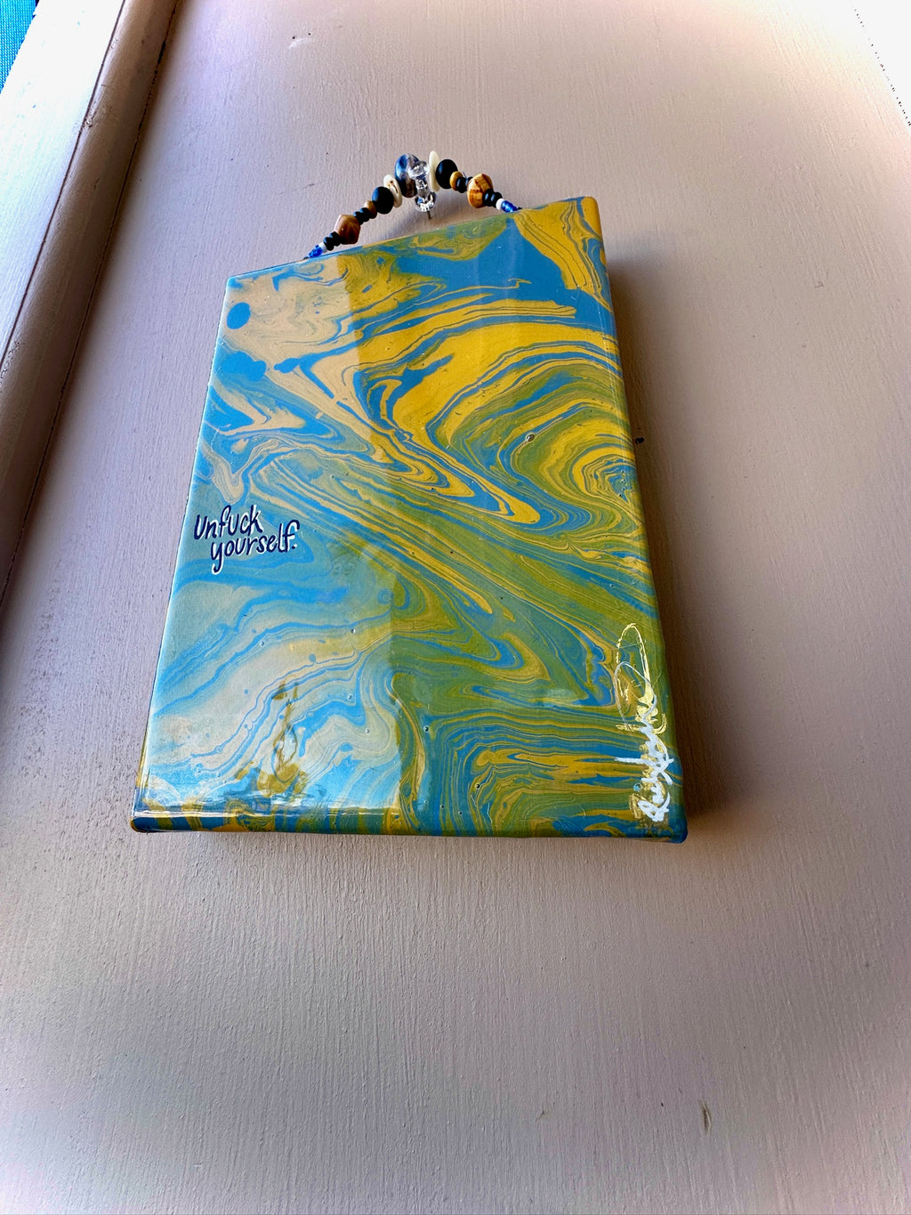 Marbled blue and yellow pouch with text on a light gray surface