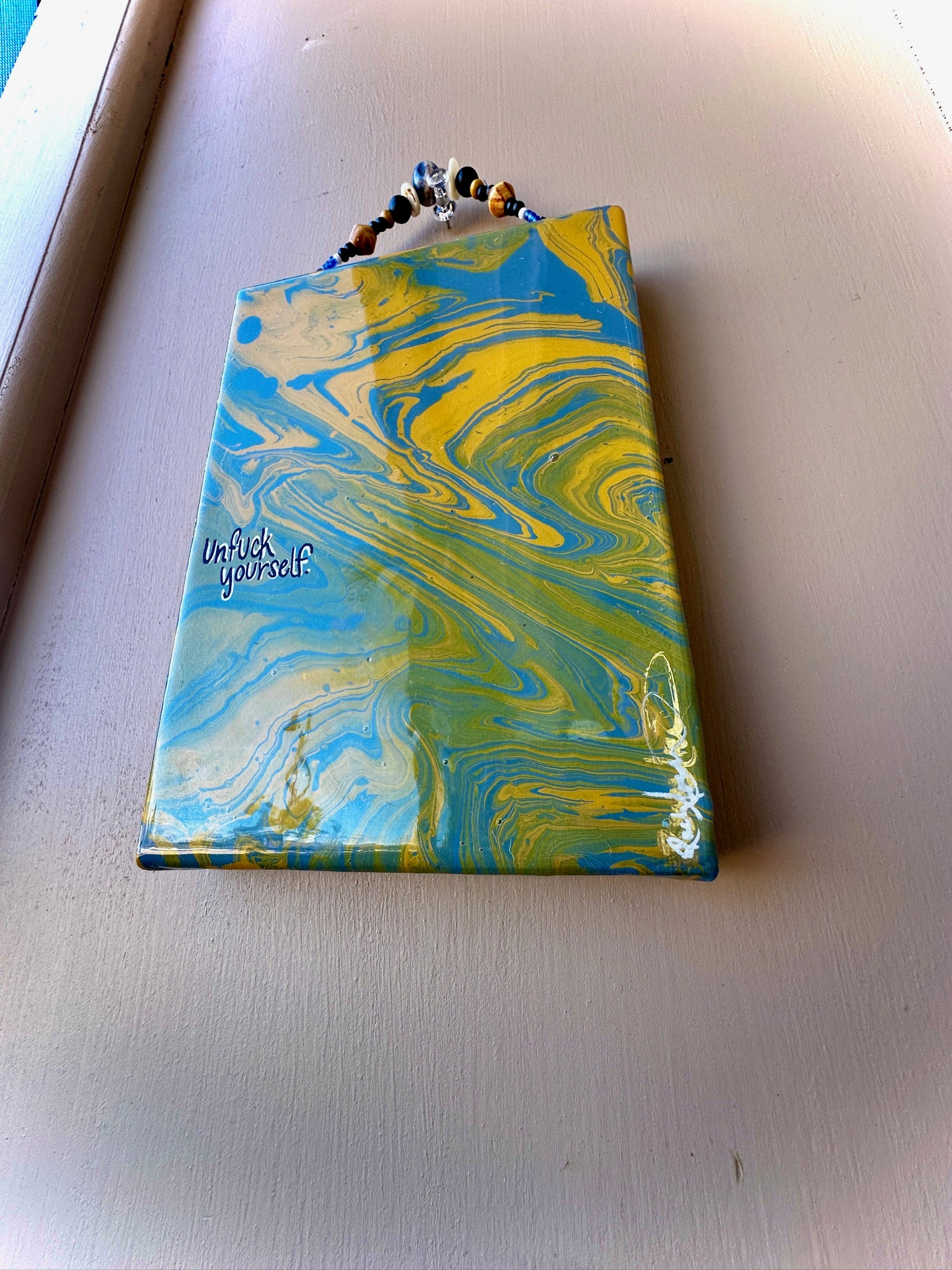 Marbled blue and yellow pouch with text on a light gray surface