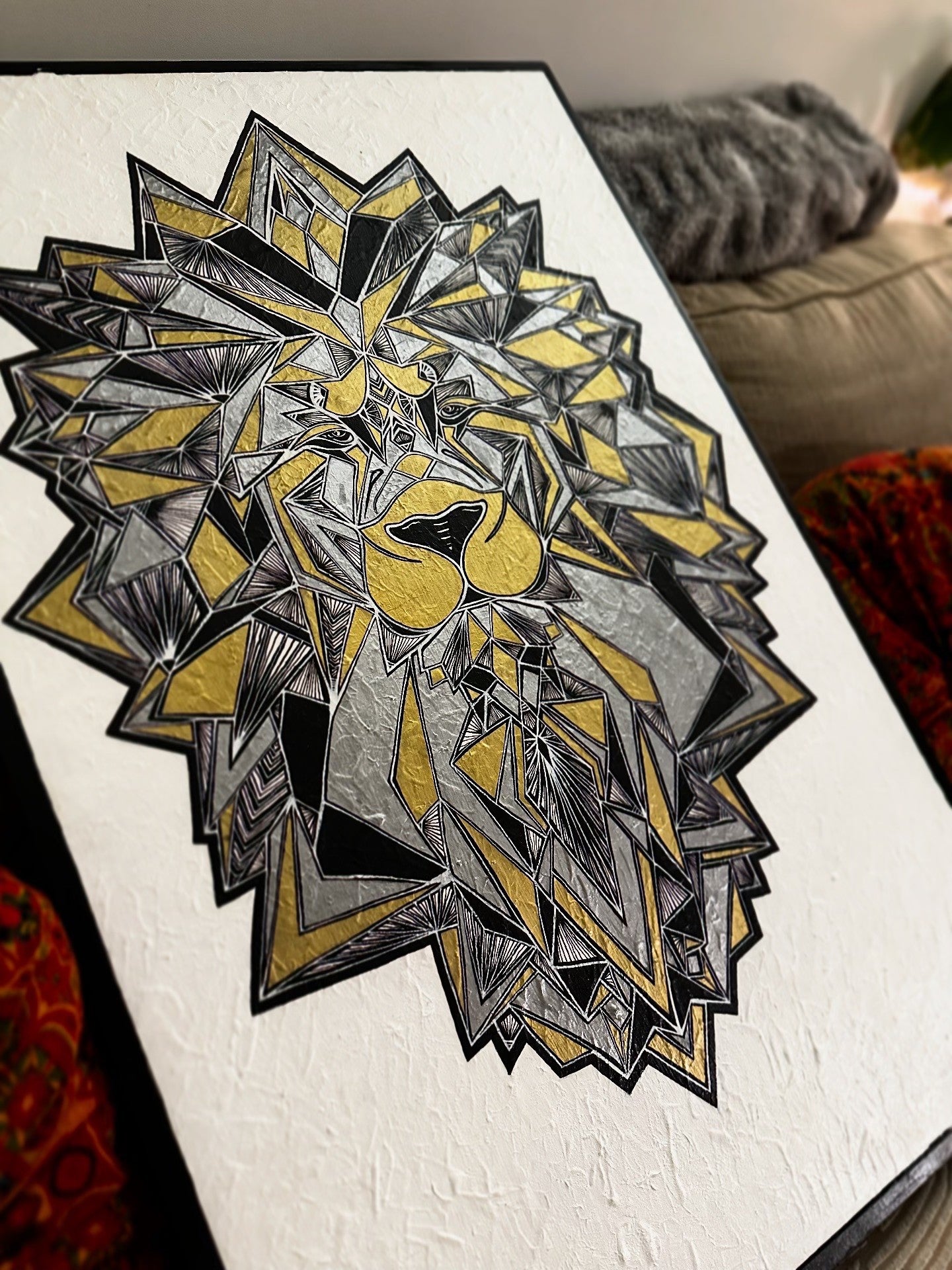 Geometric lion head design on a white surface with a blurred background