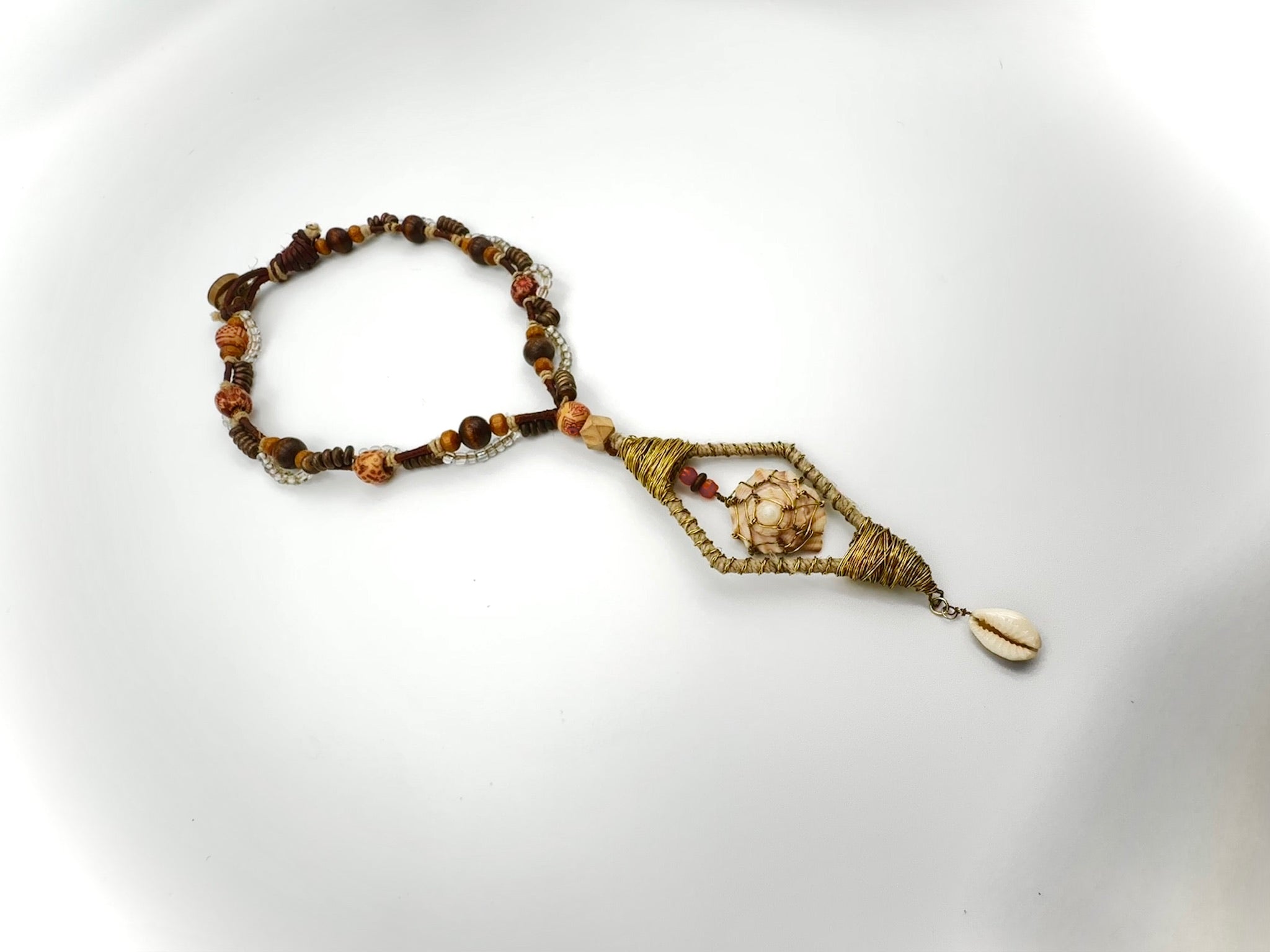 Beaded bracelet with shell charm on a white background