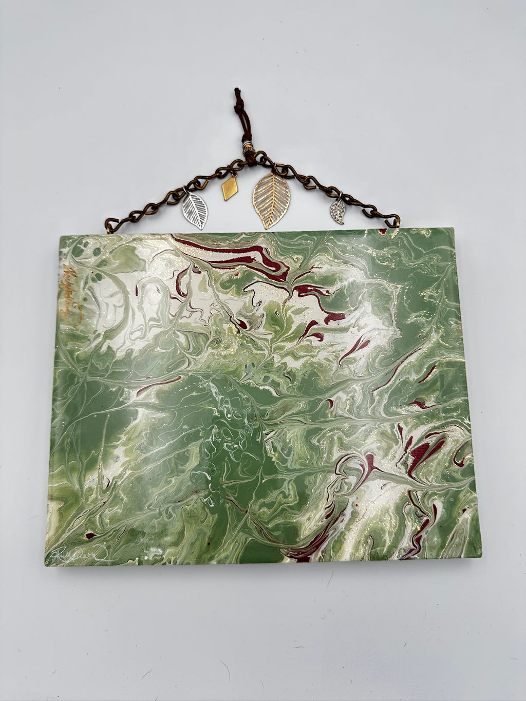 Marbleized green and white plaque with leaf decorations on a white background
