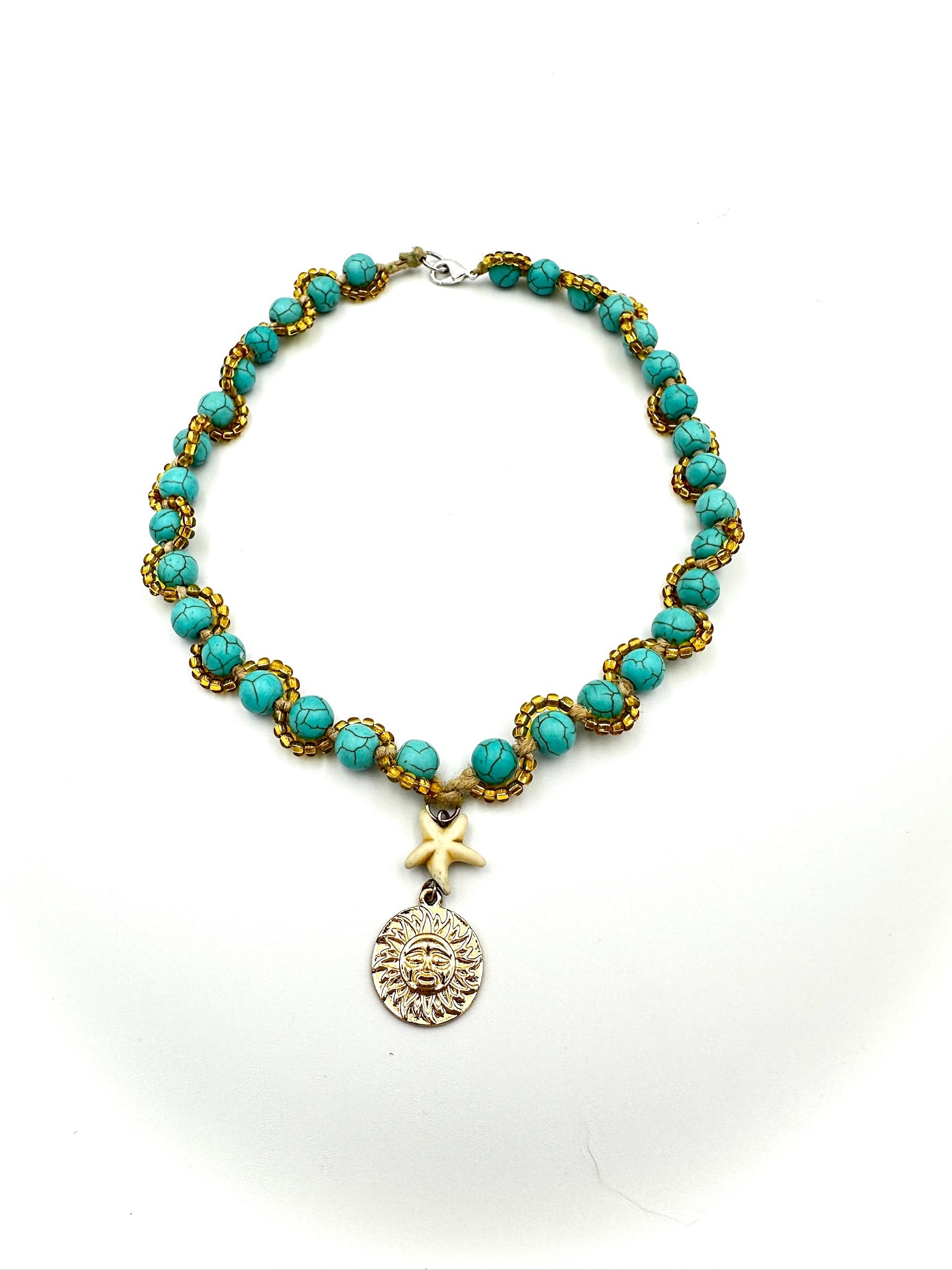 Turquoise beaded necklace with gold accents and a sun pendant on a white background