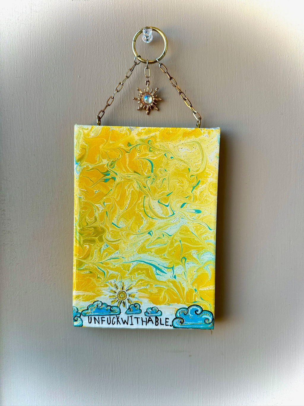 Yellow and blue marbled painting with 'UNFUDDWITHABLE' text on a plain background