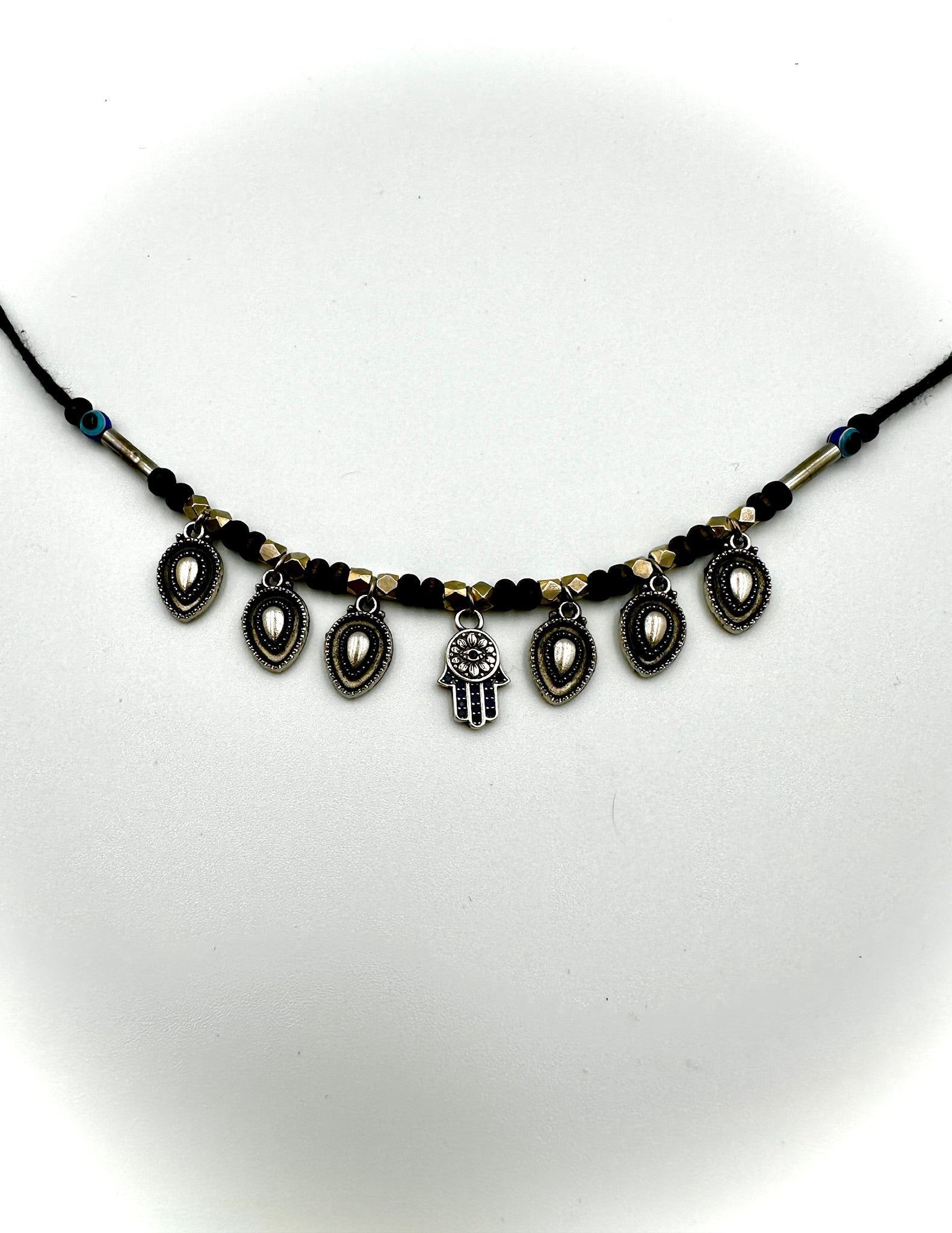 Necklace with black beads and a hamsa charm on a white background