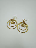 Gold hoop earrings with lotus flower designs on a light gray background