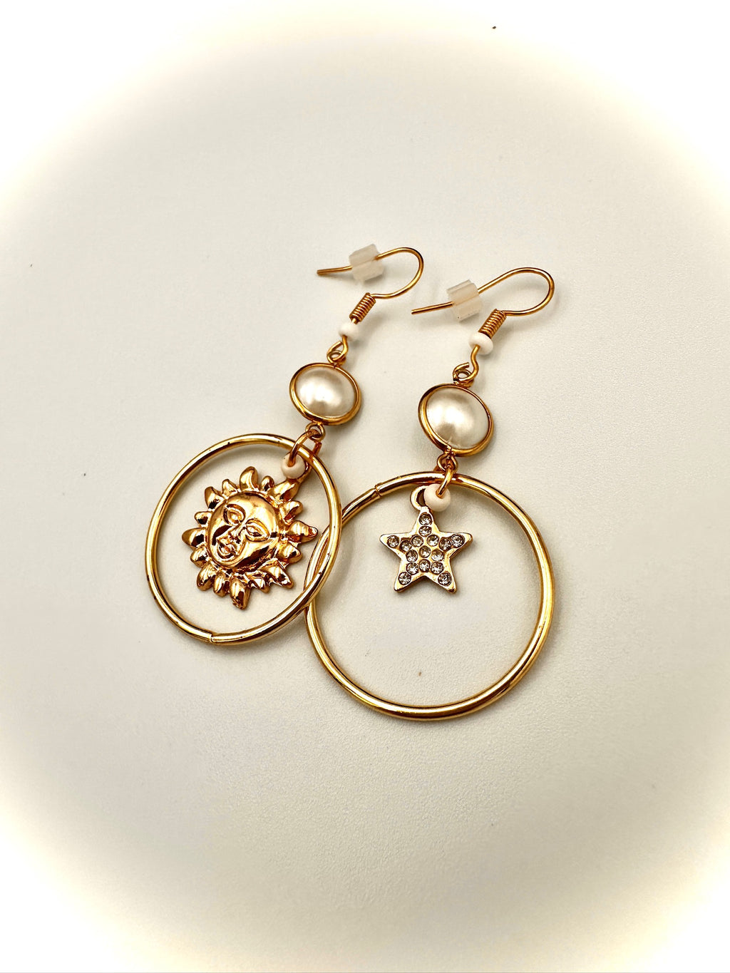 Gold earrings with star and circle designs on a light background