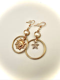 Gold earrings with star and circle designs on a light background