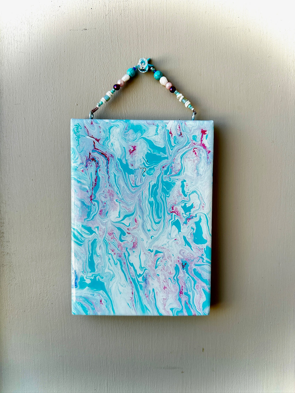 Marbled art piece with blue, pink, and white colors on a beige background