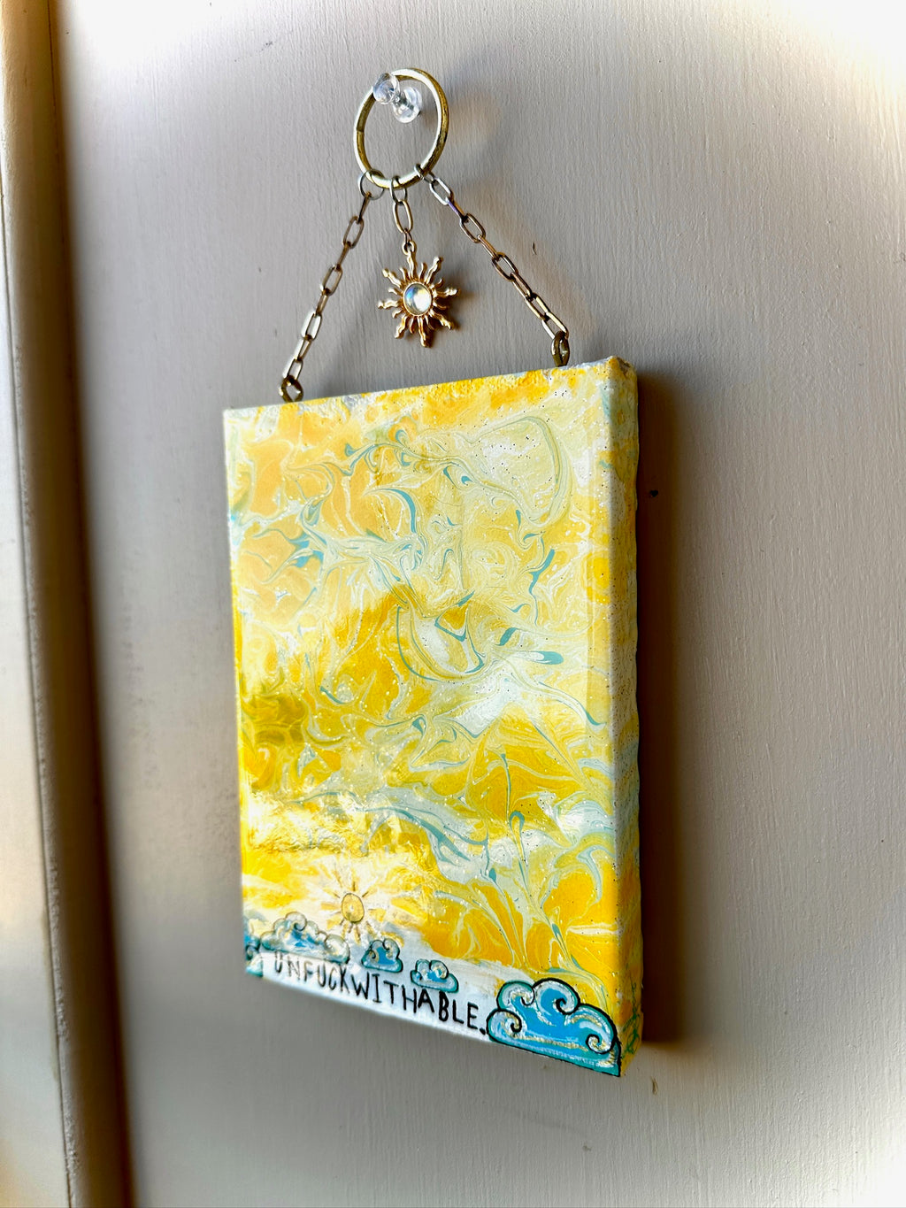 Yellow marbled keychain with a chain and decorative element on a metallic surface