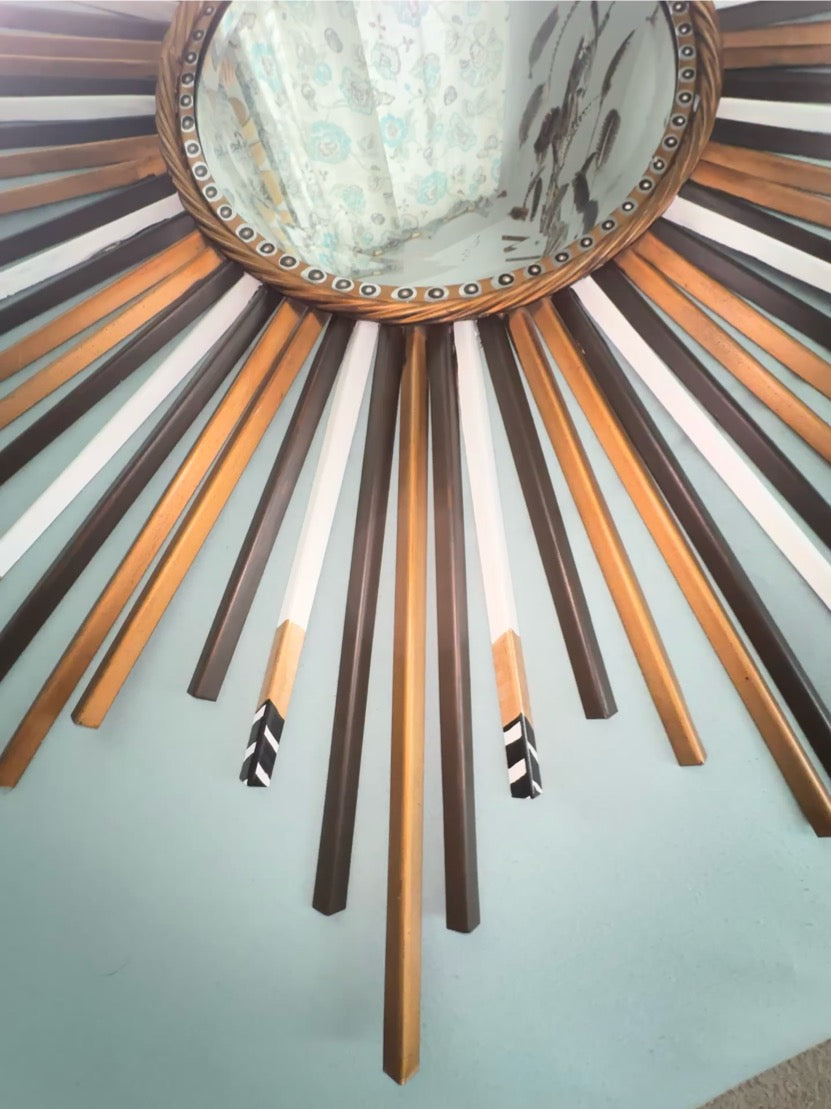 Decorative wall mirror with sunburst design on a light blue wall