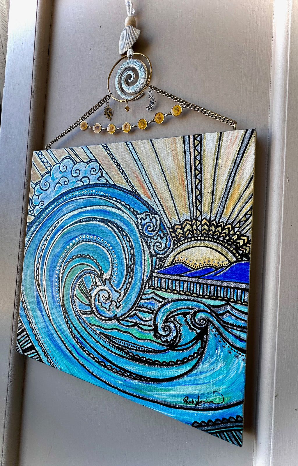 Decorative wall art with blue wave design and hanging elements on a plain background