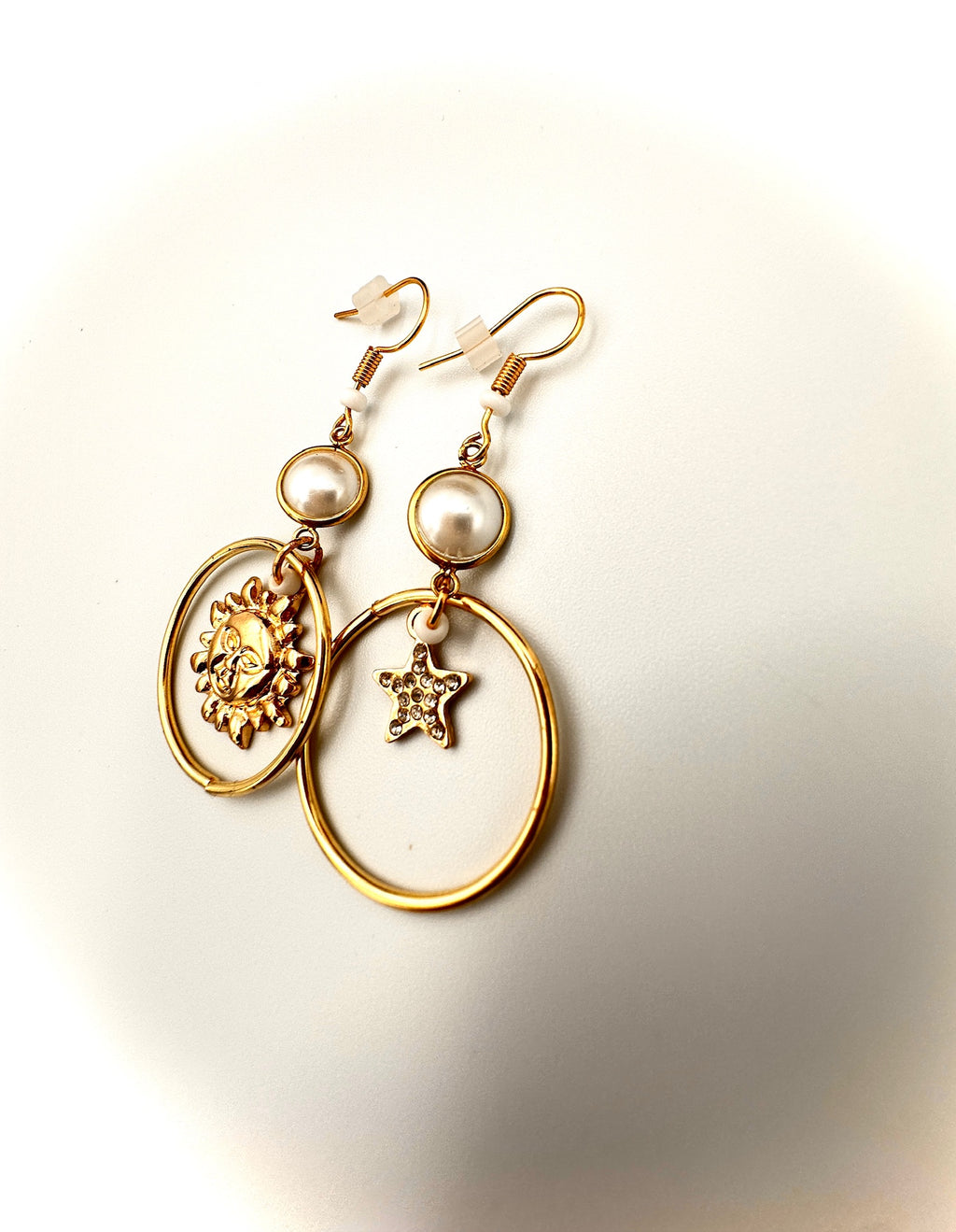 Gold earrings with pearl and star designs on a light background