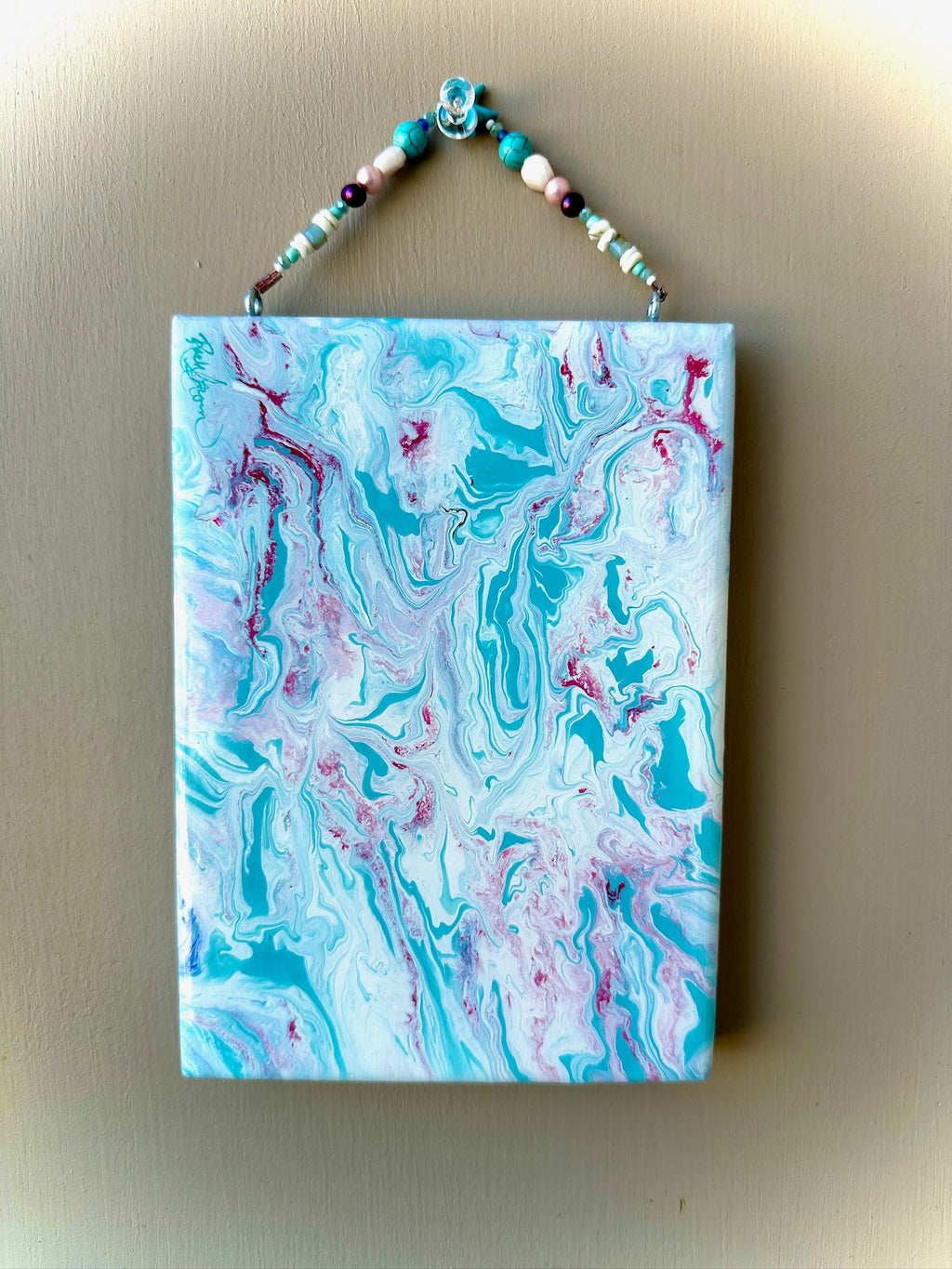 Marbled artwork with blue and pink patterns on a beige wall