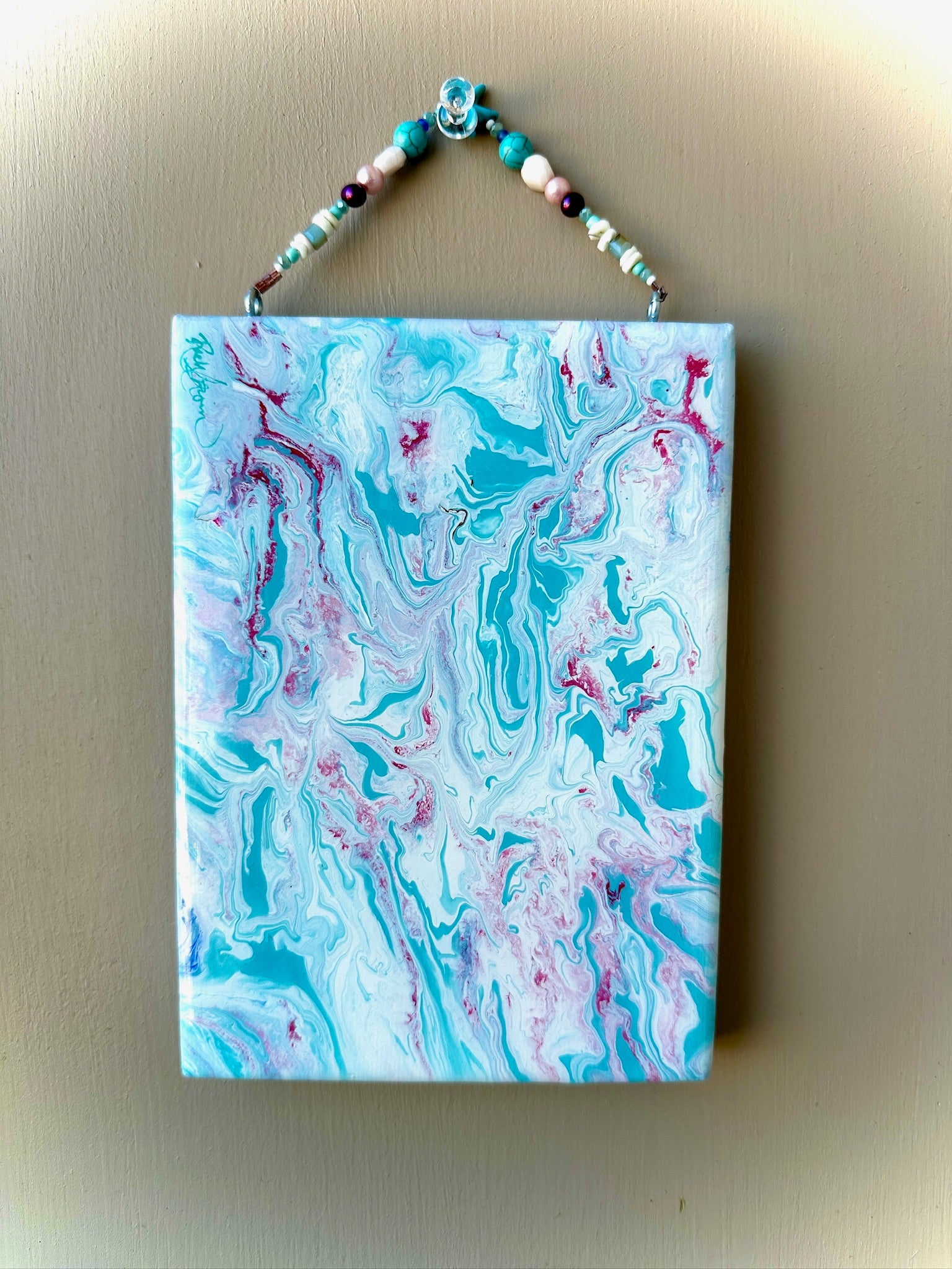 Marbled artwork with blue and pink patterns on a beige wall