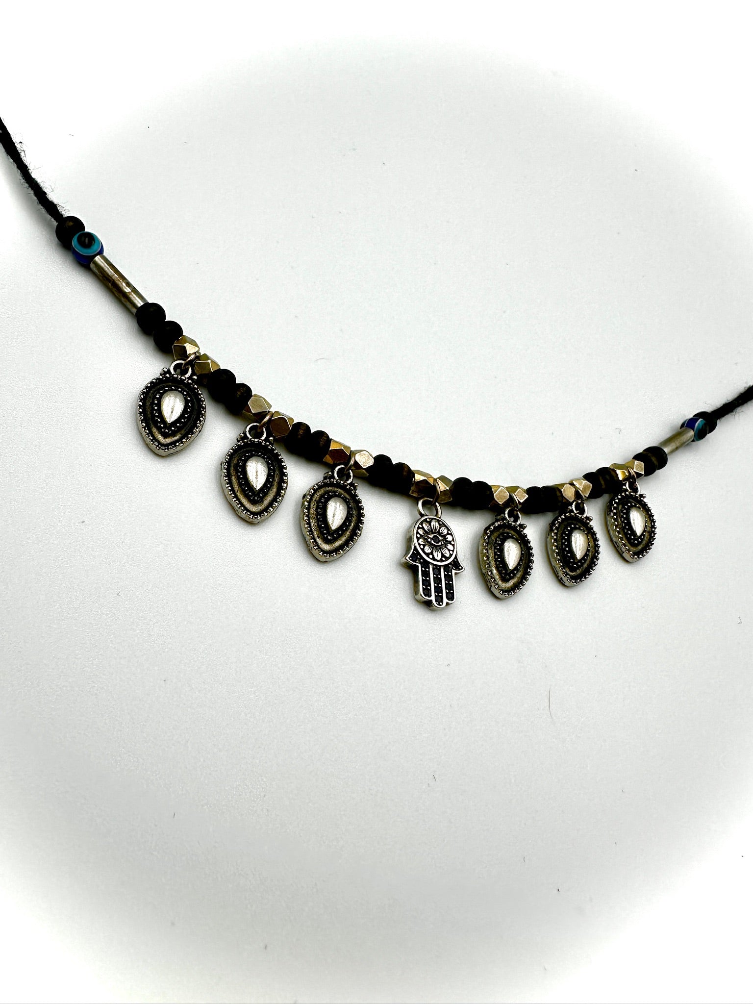 Necklace with Hamsa hand and coin charms on a white background