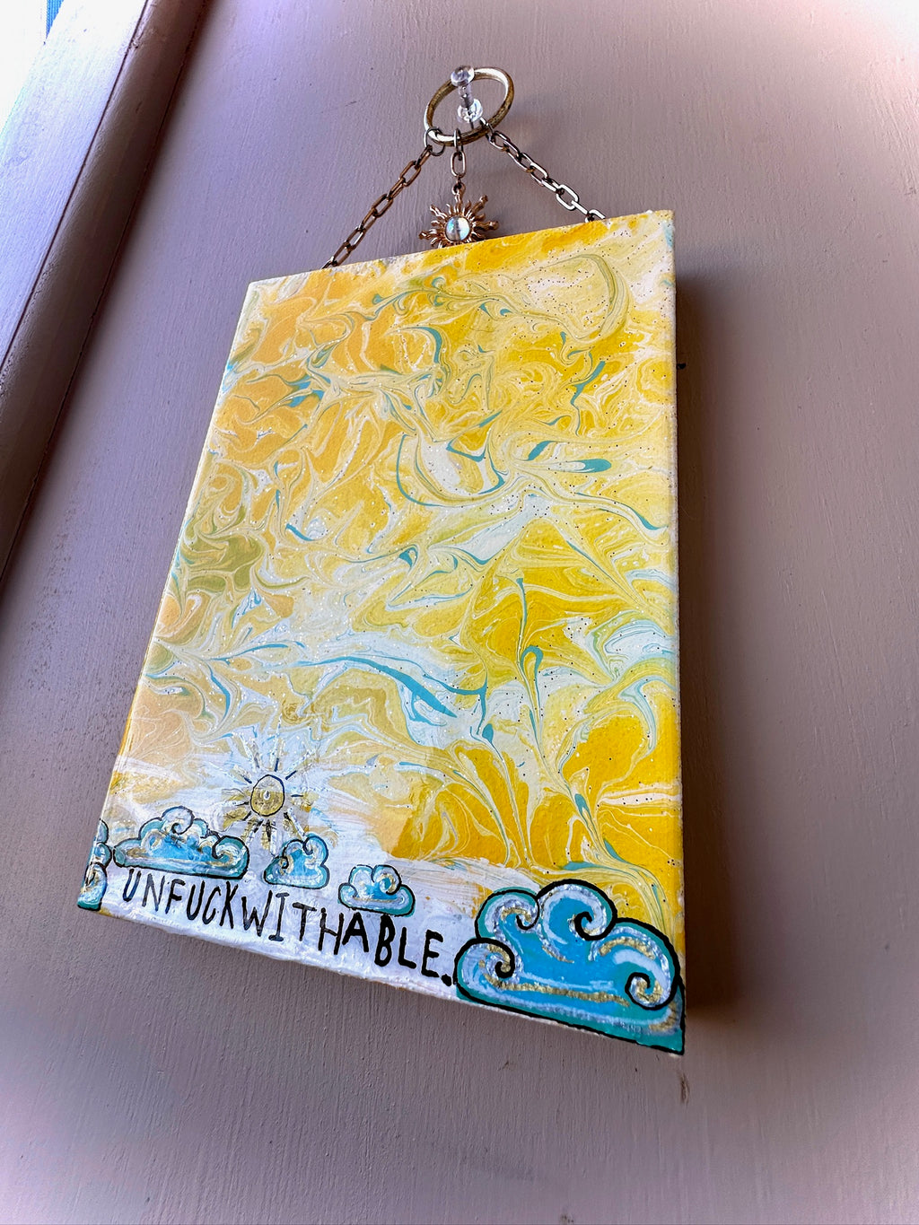 Marbled yellow and blue rectangular object with 'UNFUCKWITHABLE' text on a plain background