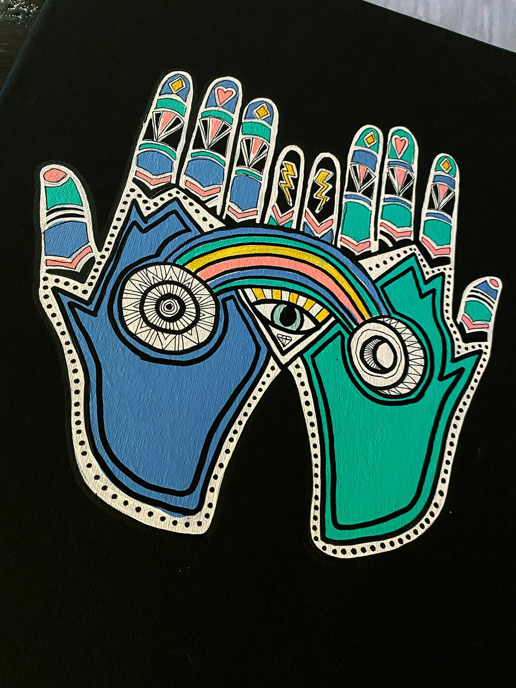 Colorful hand design with symbols and a rainbow on a black background