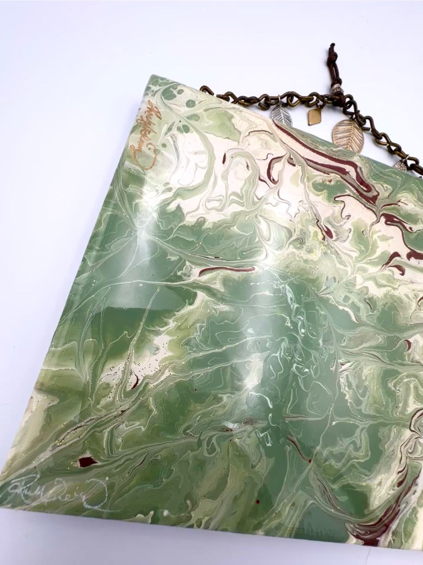 Marbled green and white surface with a necklace on a white background