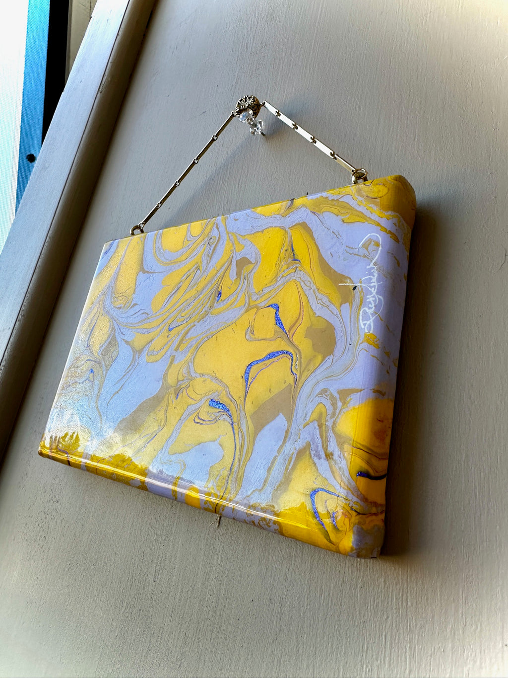 Marbled yellow and gray clutch bag on a light gray surface