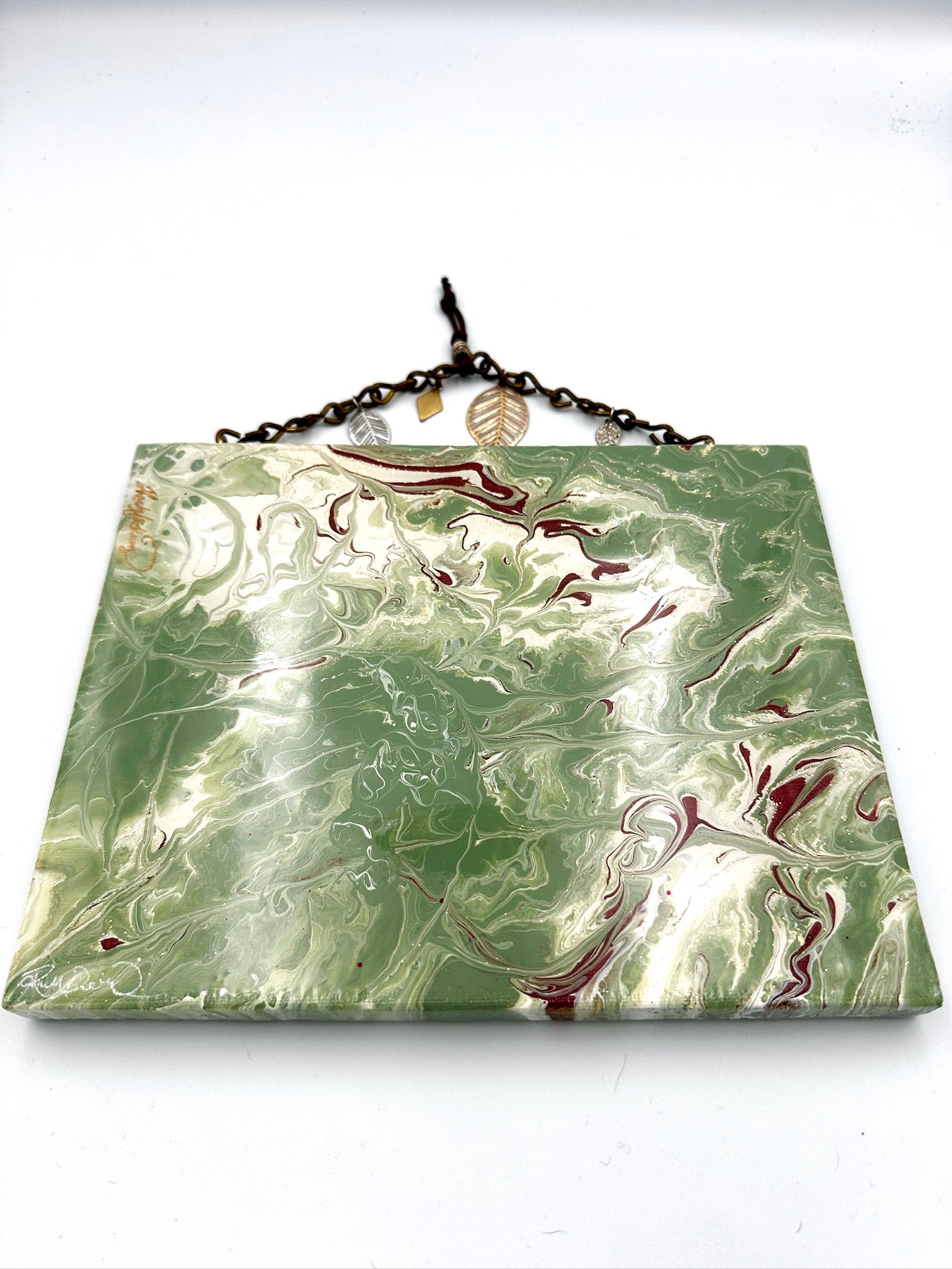 Marbled green and red square object with a chain on a white background