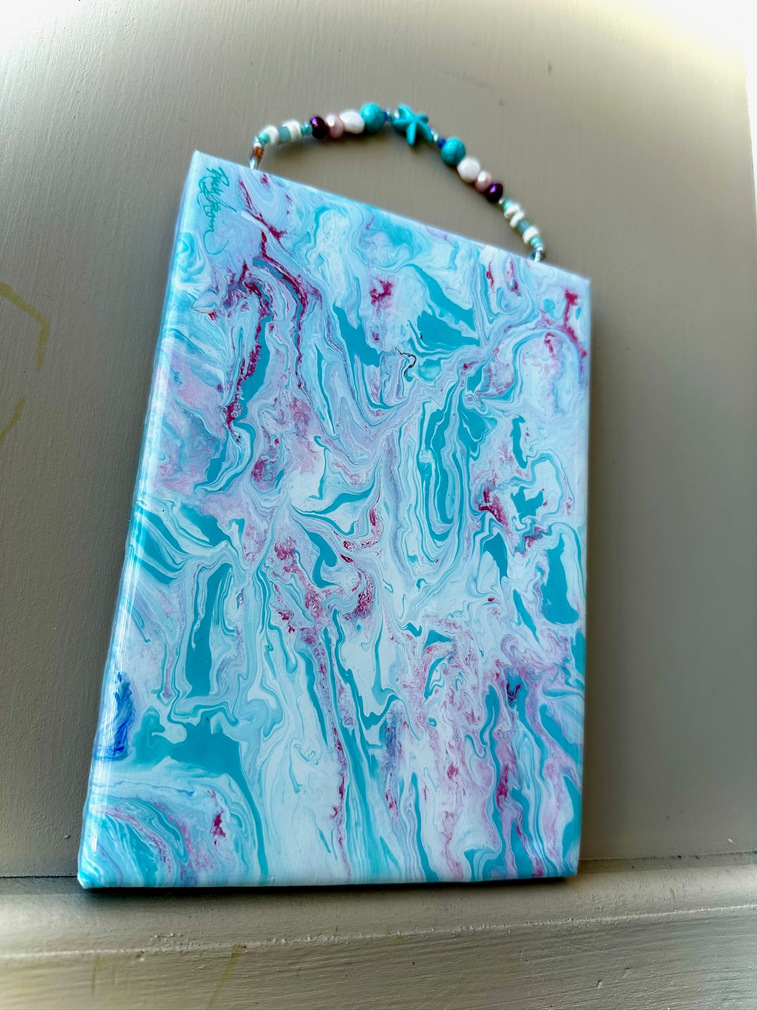 Marbled art piece with blue, pink, and white colors on a neutral background
