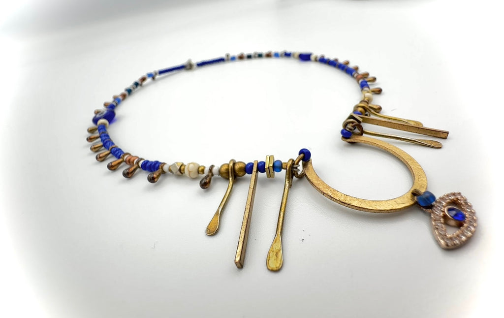 Necklace with blue beads and gold accents on a white background