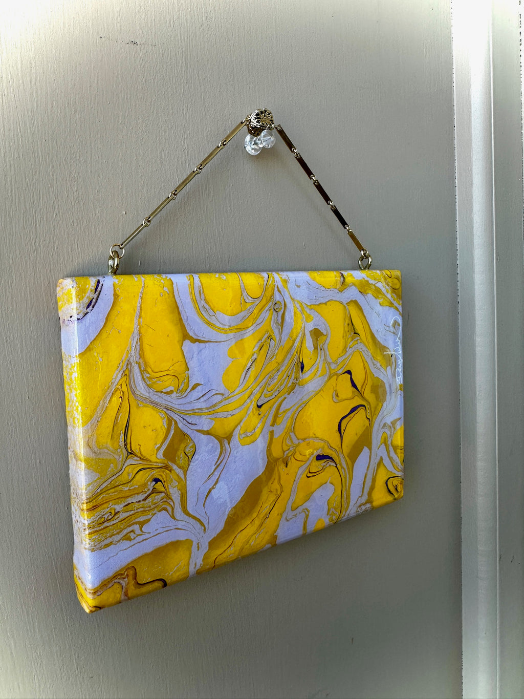 Yellow and white marbled patterned pouch hanging on a light gray wall.