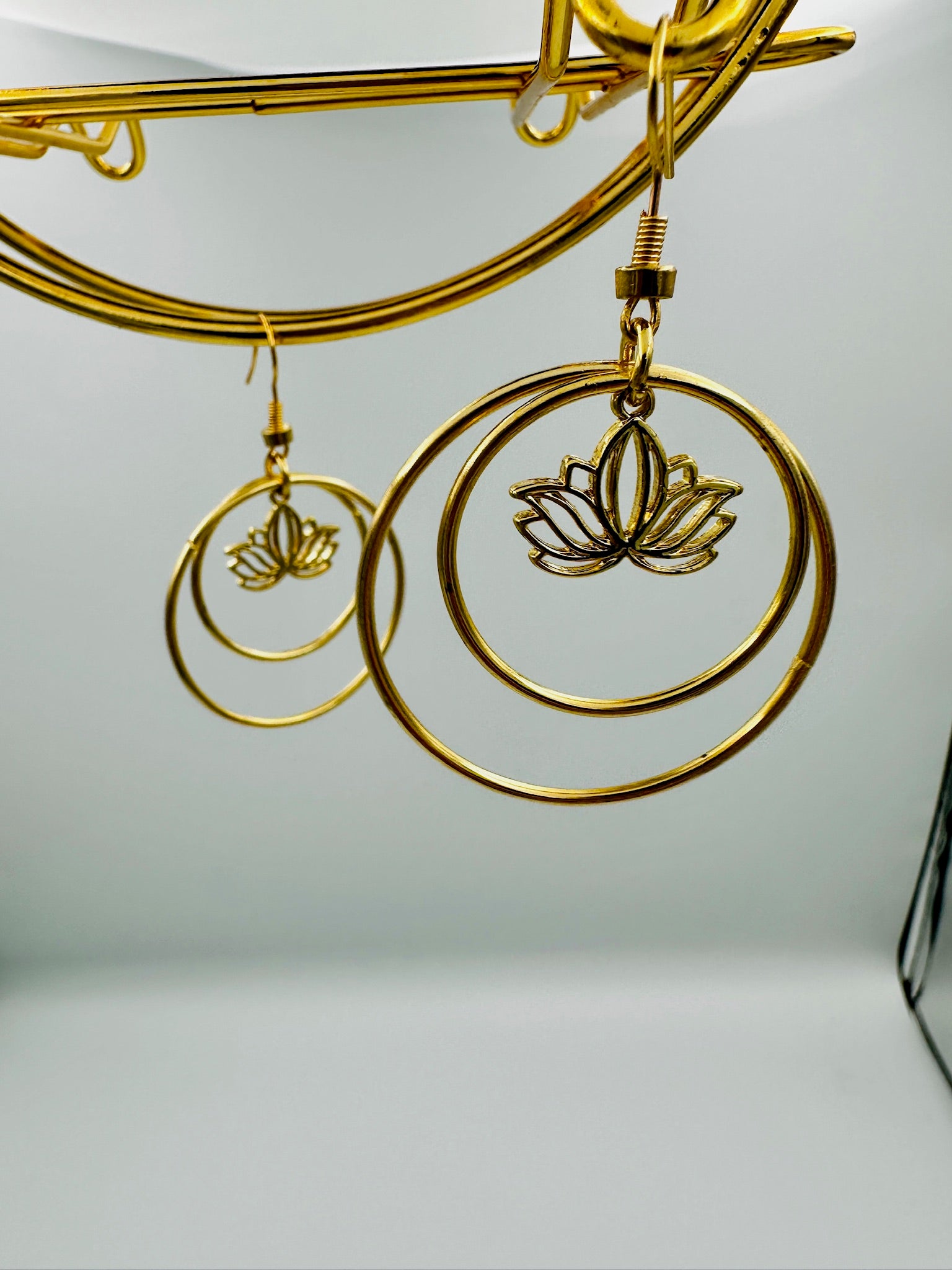 Gold lotus flower earrings on a white background