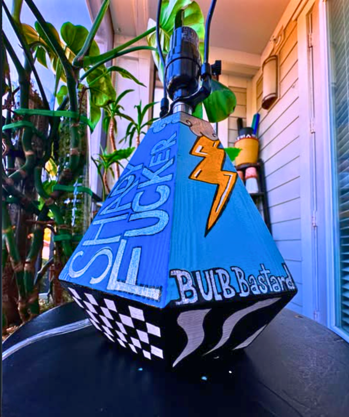 Decorative lamp with text and graphics on a checkered base, outdoors.